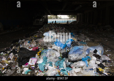 I lavoratori smistano i rifiuti in pile alla stazione di trasferimento dei rifiuti solidi di città del Messico, Messico. Foto Stock