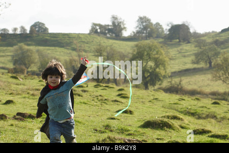 Giovane ragazzo in esecuzione con il kite in campo Foto Stock