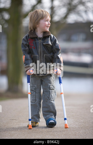 Ragazzino con una gamba rotta a camminare con le stampelle Foto Stock