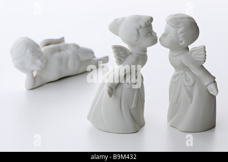 Porcellana Bianca un ragazzo e una ragazza baciare gli angeli con un terzo angelo cherubino sdraiato guardando in uno sfondo bianco Foto Stock