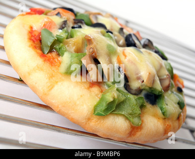 Piccola pizza conditi con formaggio, peperoni Funghi,e pomodoro su di un raffreddamento per rack Foto Stock