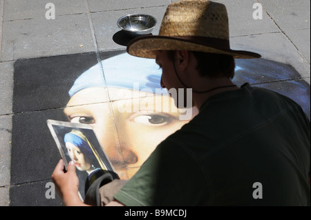 L'artista di strada disegno Ragazza con un orecchino di perla sul marciapiede. Foto Stock