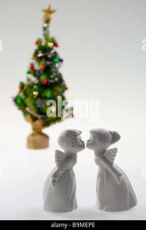 Porcellana Bianca un ragazzo e una ragazza baciare gli angeli nella parte anteriore di un albero di Natale decorato su sfondo bianco Foto Stock