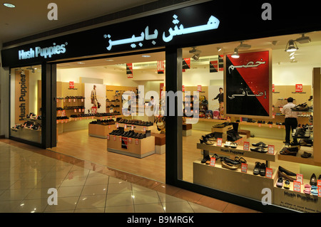 Abu Dhabi Marina shopping mall Hush Puppies marchio di vendita al dettaglio scarpa store & shop finestra anteriore display con cartello bilingue EMIRATI ARABI UNITI Medio Oriente Asia Foto Stock