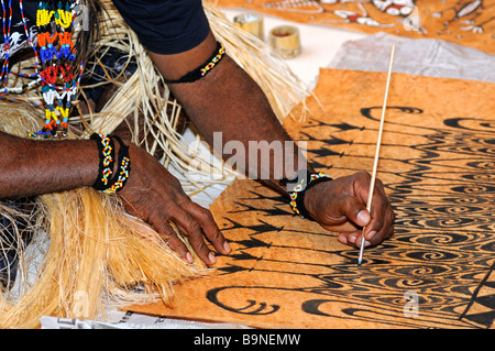 Artista locale vernici motivi tradizionali sulla corteccia dell'albero Khambouw, Lago Sentani area, Papua occidentale, in Indonesia Foto Stock