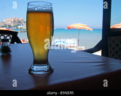 Di fronte al mare, con una birra e sun umberellas Calvi, Corsica, Francia. Foto Stock