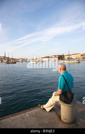 Maschio per turisti in cerca del mare sul lungomare di Rovigno, Istria, Croazia, con vista della torre campanaria e il porto in background Foto Stock