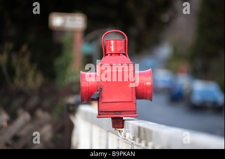 Stazione della Guardia dipinte di rosso olio lampada montato su di un incrocio ferroviario barriera Foto Stock