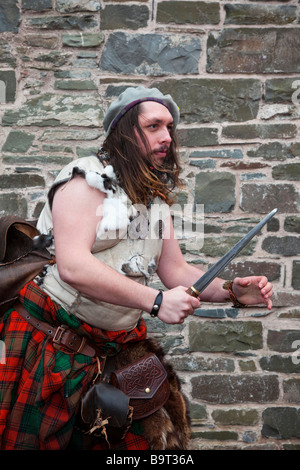 Highlander scozzese. L'uomo indossando il tradizionale kilt & holding pugnale, sgian dhu dirk a Hawick festival Reivers, Scottish Borders, Hawick Scozia, Regno Unito Foto Stock