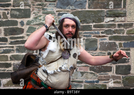 Highlander scozzese. L'uomo indossando il tradizionale kilt & holding pugnale, sgian dhu dirk, a Hawick festival Reivers, Scottish Borders, Hawick Scozia, Regno Unito Foto Stock