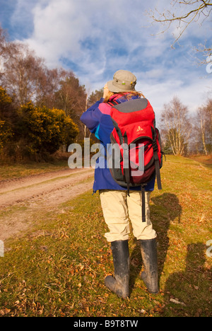 Una donna birdwatching guardando attraverso il binocolo nel paese Foto Stock