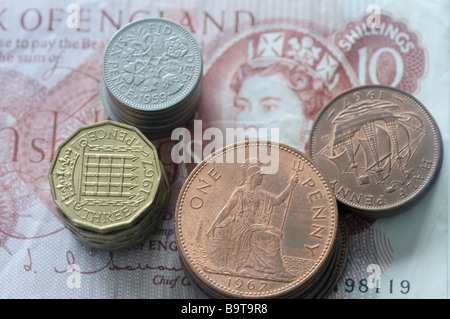 Pile di vecchie monete Britanniche su dieci scellino nota Foto Stock