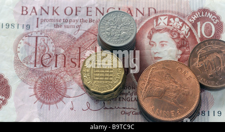 Pile di vecchie monete Britanniche su dieci scellino nota Foto Stock