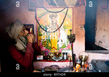 Un sadhu fuma la sua chilum dentro il suo piccolo tempio home. Foto Stock