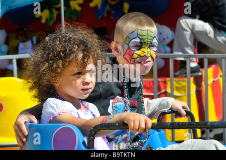 Multi etnico bambini sulle giostre di Midway a Mardi Gras celebrazione nel Lago del Galles Centrale della Florida USA Foto Stock