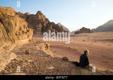 Un turista si siede a guardare il tramonto nel deserto, Wadi Rum, Giordania Foto Stock