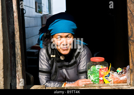 Un Akha / Hani donna sorride dal suo negozio locale in un piccolo villaggio nella regione di YuanYang o Yunnan in Cina. Foto Stock