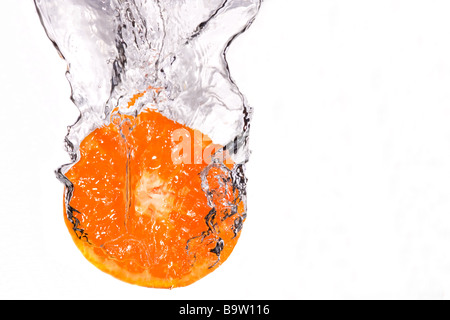 Fetta di arancia schizzi in acqua su sfondo bianco Foto Stock