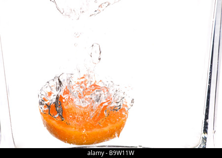 Orange è scesa in acqua contro uno sfondo bianco Foto Stock