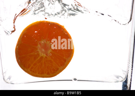 Fetta di arancia in acqua contro uno sfondo bianco Foto Stock