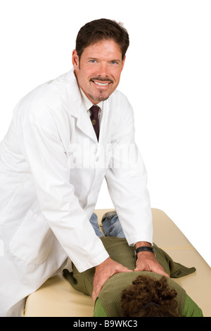 Bello chiropratico sorrisi come egli regola un paziente isolato su bianco Foto Stock