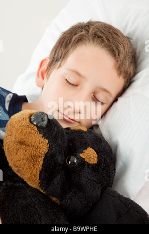 Adorable little boy suono addormentato accanto al suo peluche Foto Stock