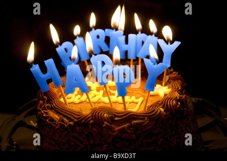 Una torta di compleanno con lettera illuminato candele ortografia buon compleanno. Foto Stock