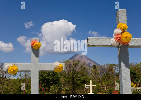 Fiore marchio attraversa le tombe a Cementerio Los Angeles in Moyogalpa, Nicaragua sull isola di Ometepe con Volcan Concepcion profila dietro. Foto Stock