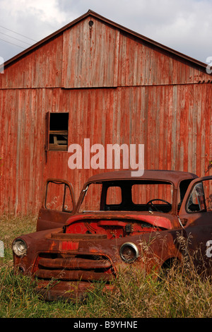 Ho abbandonato una vecchia auto rossa arrugginita in un'auto d'epoca aperta e arrugginita sul campo con un deposito di fienile nel Michigan USA nessuno ad alta risoluzione verticale Foto Stock