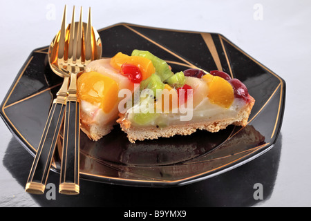 Flan di frutta con kiwi le pesche e le ciliegie su un sfondo riflettente Foto Stock