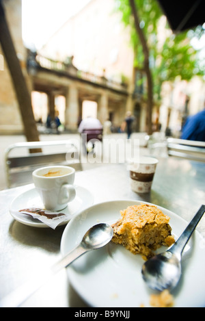 Tazza di caffè e mezza mangiato pasta sulla sinistra cafè sul marciapiede tabella Foto Stock