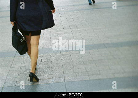 Imprenditrice camminando sul marciapiede, vista posteriore, ritagliato Foto Stock