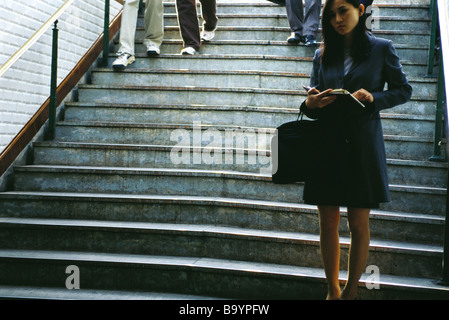 Imprenditrice permanente al fondo di passi, tenendo agenda aperta Foto Stock