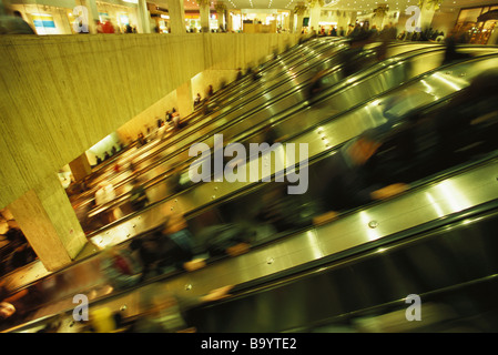 Scale mobili in affollato centro commerciale per lo shopping Foto Stock