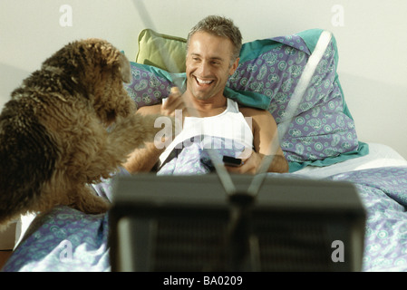 Uomo a giocare con il cane a letto Foto Stock