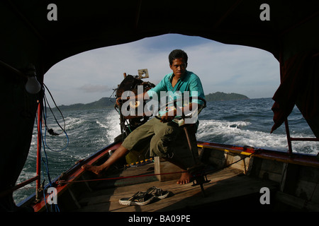 Un uomo tailandese opera la sua longtail boat vicino l'isola tropicale di Koh Ngai e Trang, sulla costa occidentale della Thailandia. Foto Stock