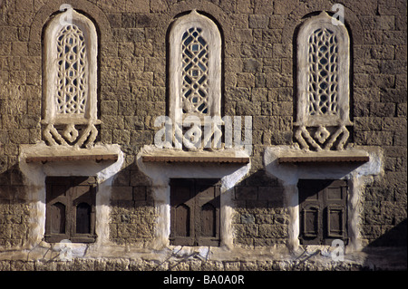 Triple arredate Windows & ante di un Adobe Mattone di fango casa torre, Sana'a o a San'a, Repubblica dello Yemen Foto Stock