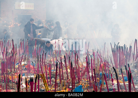 La gente facendo offerte di candele, bastoncini di incenso e bruciando denaro cartaceo per placare gli spiriti degli antenati in Cina. Foto Stock