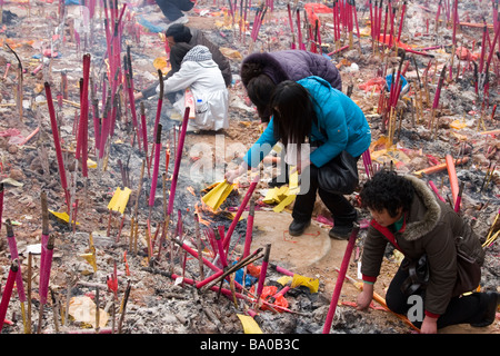 La gente facendo offerte di candele, joss bastoni e bruciare la carta moneta per placare gli spiriti degli antenati in Cina. Foto Stock