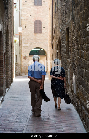 I residenti locali sul loro modo a casa dal mercato settimanale in Piazza del Duomo, San Gimignano, Toscana, Italia. Foto Stock