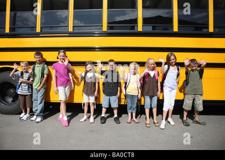 Gruppo di scolari nella parte anteriore del bus di scuola Foto Stock