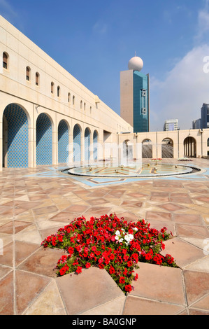 Abu Dhabi la Fondazione culturale cortile pavimentato e fontana con rosso fiori di petunia Foto Stock