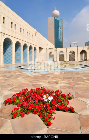 Abu Dhabi la Fondazione culturale cortile pavimentato e fontana con rosso fiori di petunia Foto Stock