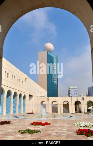 Abu Dhabi la Fondazione culturale cortile pavimentato e fontana con rosso fiori di petunia incorniciato da arch Foto Stock