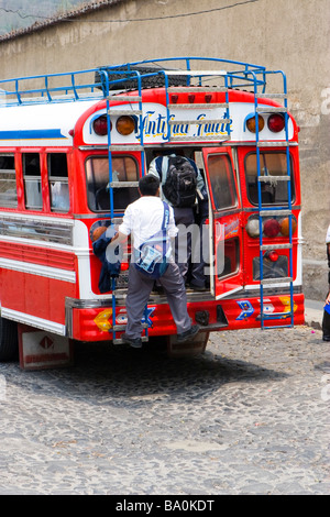 Ragazzo guatemalteco il luppolo su un locale bus di pollo attraverso la porta di Antigua Guatemala Foto Stock