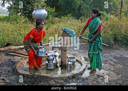 Due donne indiane della tribù Paroja ridendo e sorridendo mentre la raccolta di acqua dal pozzo del villaggio Foto Stock