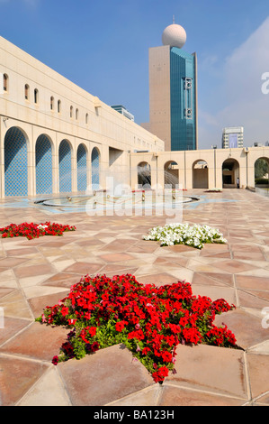 Abu Dhabi la Fondazione culturale cortile pavimentato e fontana con rosso fiori di petunia Foto Stock