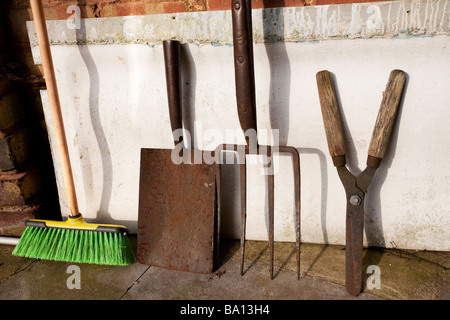 Attrezzi da giardino appoggiata contro un muro di mattoni Foto Stock