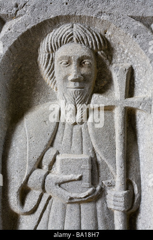San con una croce e una Bibbia. Un rilievo scolpito sul lato di una bara nella famosa e antica abbazia. Foto Stock