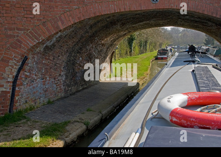 Longboat barca passando sotto il ponte sul Grand Union Canal Foto Stock